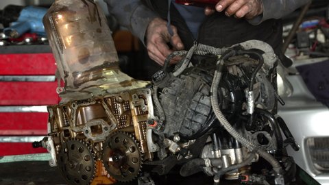 Workshop Master Checks Cylinder Head of a Dismantled Vehicle Engine Through His Eyes
