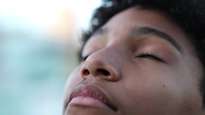 Mix race child opening eyes to sky smiling with hope.