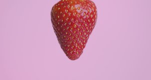 Strawberry jam flows down on natural red berry on pink studio background with copy space, sweet tasty fresh vitamins