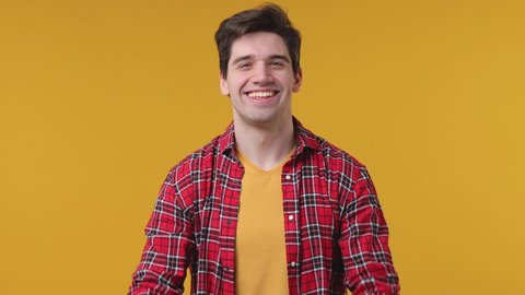 Overjoyed young man 20s in red checkered shirt posing isolated on yellow background studio. People lifestyle concept. Count countdown 1 2 3 one two three doing winner gesture clapping hands screaming