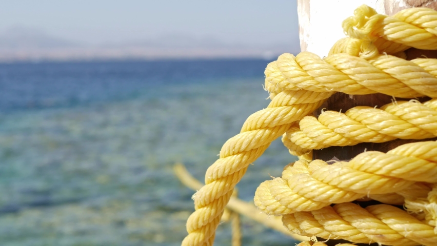 Mooring bollard and tethered rope on the shore of a sea