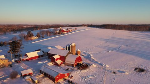 Aerial establishing shot of a Farm house in winter. Rural landscape, countryside. Cold freezing weather, snow, sunrise (sunset). Camera (drone) moves backward