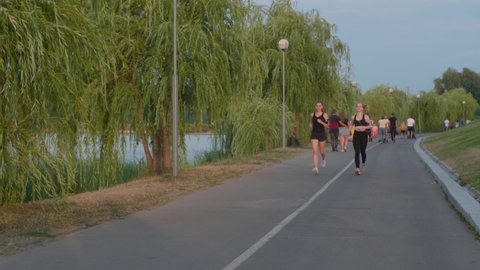 Beautiful girls are jogging in the park. Young women run around the park for their health. The concept of sports and rejuvenation.