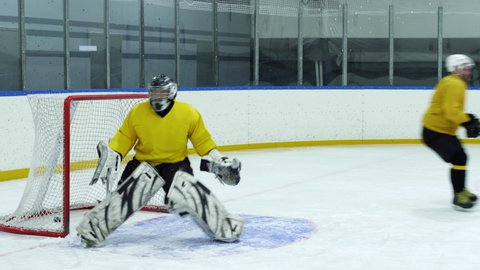 Ice hockey goaltender in sports uniform defending gate on rink but missing puck during game
