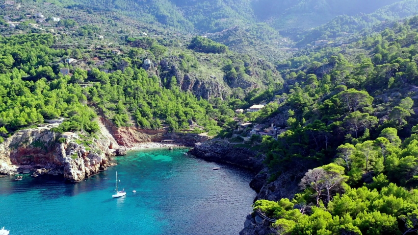 Cala Deia cove in Mallorca Spain with white yachts anchored, Aerial dolly out shot