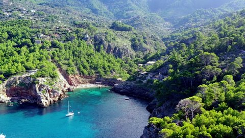 Cala Deia cove in Mallorca Spain with white yachts anchored, Aerial dolly out shot