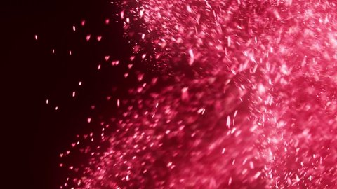 Bokeh of sparkling glittering lights in the shape of hearts flowing and falling across the screen, glowing in red and pink. Magical romantic abstract background.