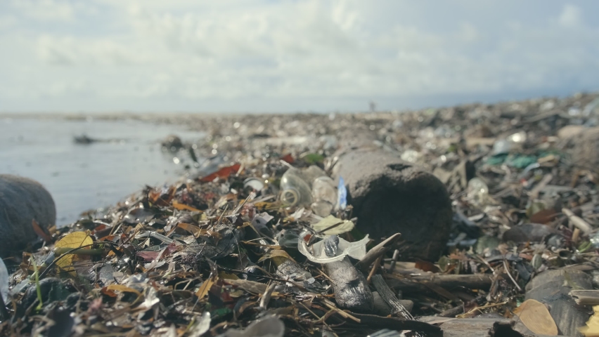 Dirty sea sandy shore environmental pollution ecological problem. Spilled garbage on ocean beach coast Bali island empty used dirty plastic bottles and other chemical waste. | Shutterstock HD Video #1066978333