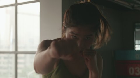 Close up of Asian robust women boxing in air. Chinese female in gym to strengthen arm's muscle and do fitness workout indoors,professional exercise routine,self-training to build body shape 4k.