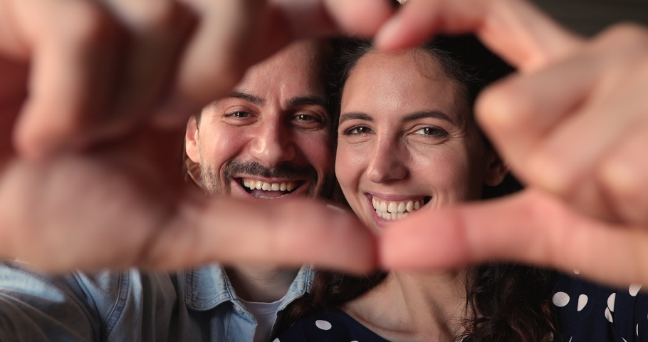 Close up happy lovely couple faces look through joined fingers making heart shape, bloggers give to followers their love, express gratitude, St Valentines Day celebration, romantic relations concept | Shutterstock HD Video #1066988794