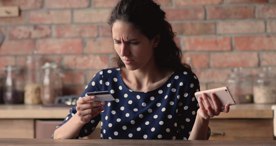 Woman hold cellphone and credit card experiencing financial problem while makes transaction, feels irritated due lack of money, debit card blocking, internet fraud and scam, empty bank account concept | Shutterstock HD Video #1066988839