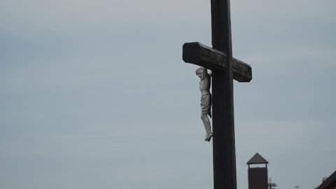 Close-up, on dark wooden cross, figurine of crucified jesus christ on street in cloudy weather