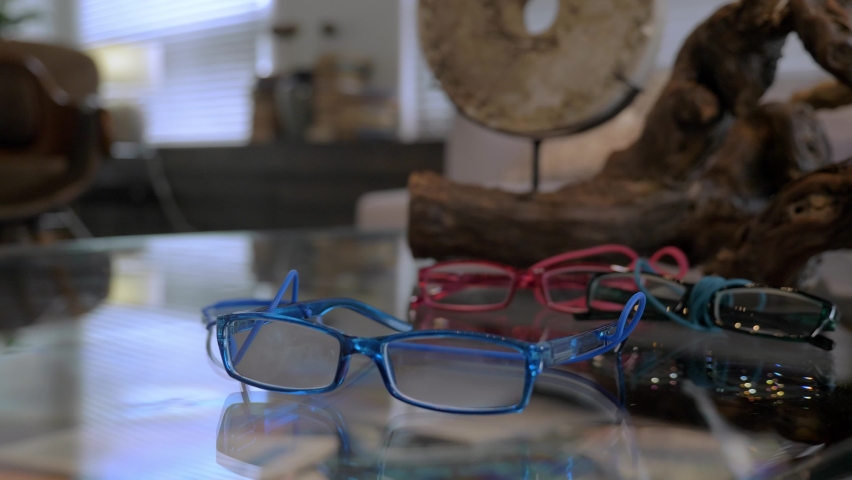 A close up look at the blue glasses lying on the table alongside red glasses and black glasses