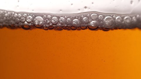 Pouring beer into glass. Closeup slow motion shot. Bubbles rising up
