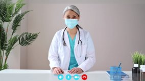 Webcam screen view. Mature gray-haired female doctor wears medical mask, looks at camera, consults the patient. Remote online medical consultation, medicine distance services, virtual medical help