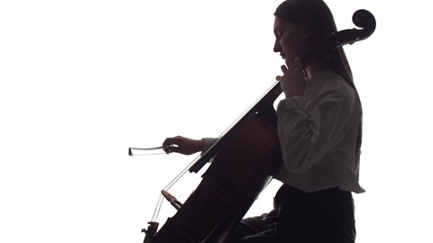 Silhouette of a girl playing the cello on a white background in the studio. The concept of wind instrument art, orchestra, passion for music, sound, precision