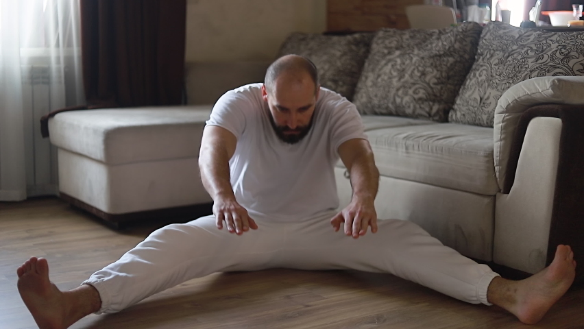 Funny overweight man doing yoga trying to do stretching