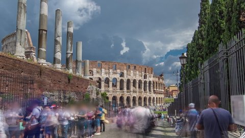 Many tourists in queue to Roman Forum and The Colosseum on background timelapse hyperlapse, also known as the Flavian Amphitheatre in Rome, Italy. Cloudy blue sky