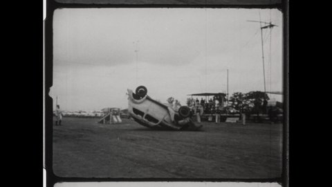 1940s Indianapolis, IN. Stuntman and Daredevil performs at Indiana State Fair. The Stuntman Flips Car Over as Spectators Watch. 4K Overscan of Vintage Arichival 16mm Film Print