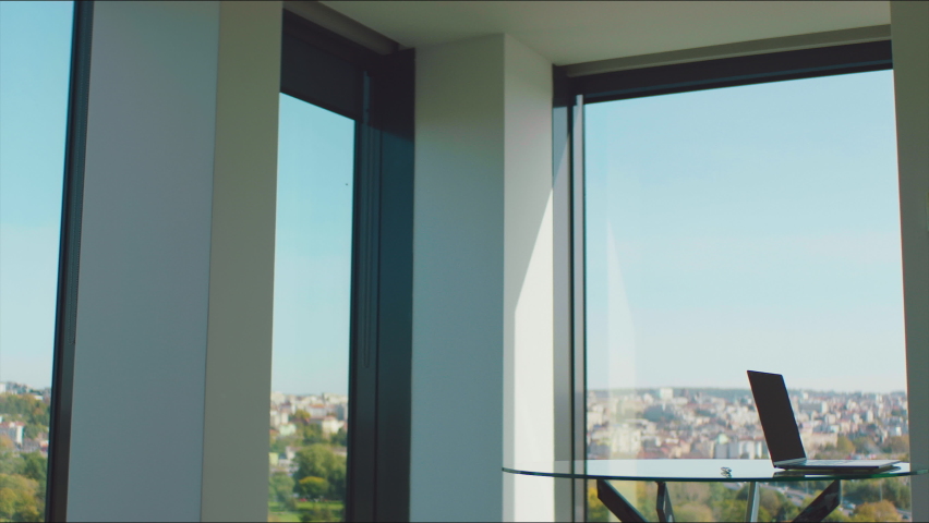 A businesswoman wearing a protective face mask and talking on the phone by the big office window.