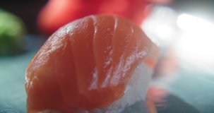 Close-up of a beautiful serving of nigiri sushi with salmon on a rotating plate. Japanese traditional cuisine. Japanese food delivery. Slow motion 4K video