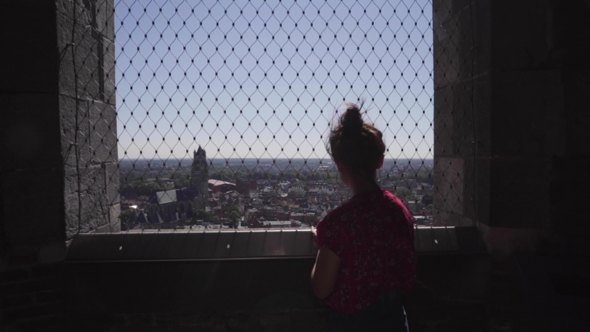 Woman enjoying the view from a church tower over the city on a calm sunny summer day in Belgium. Dolly shot