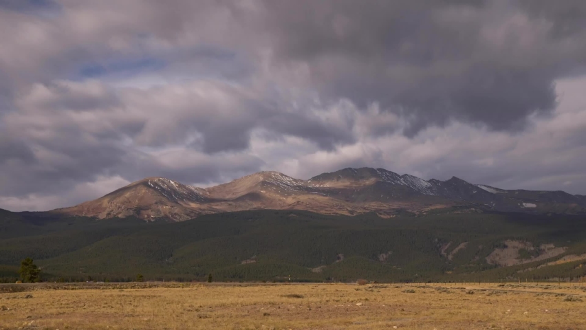 Stormy dark clouds flowing over the Mount Massive with snow on peak. Time lapse panorama shot.