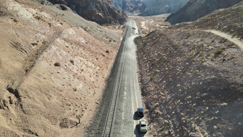 Vehicles off-roading past a creek and train truss bridge in Afton Canyon, Mojave Desert, California.
