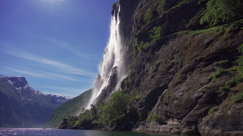 Stunning view of the beautiful Seven Sisters waterfall in the Geiranger fjord, Norway. Powerful streams of raging water fall from the 250m high jagged cliffs joining with the calm waters of the sea. Royalty-Free Stock Footage #1067033569