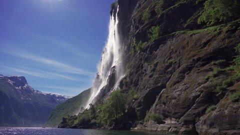 Stunning view of the beautiful Seven Sisters waterfall in the Geiranger fjord, Norway. Powerful streams of raging water fall from the 250m high jagged cliffs joining with the calm waters of the sea.