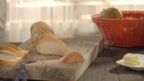 Woman slicing fresh french bun with a sharp knife in the kitchen to make breakfast. Special gluten-free bread for people on diet, healthy eating. Delicious lunch.
