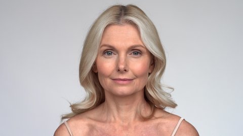 Confident beautiful fresh 50s middle aged mature woman looking at camera. Close up portrait. Anti age healthy face skin care beauty, older skincare cosmetic, cosmetology and dermatology concept.