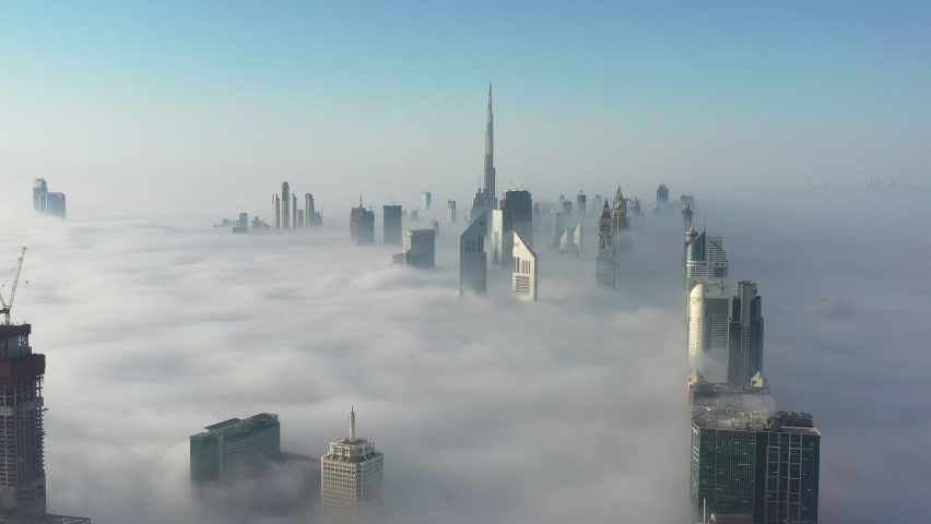 Aerial birds eye view of Dubai city urban futuristic skyline during fog; World's tallest building and high rise skyscrapers covered in dense fog in Dubai winter season | Shutterstock HD Video #1067036005