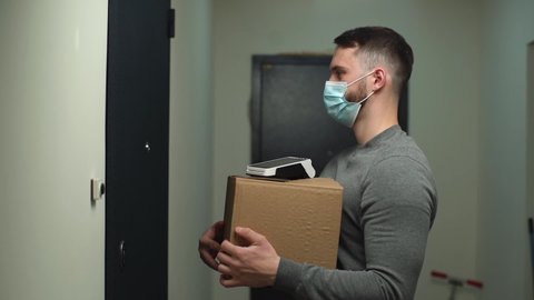 Delivery man wearing medical mask coming to door with parcel and contactless payment terminal, rings doorbell to meet customer and hand over online order. Courier waiting client in entryway.