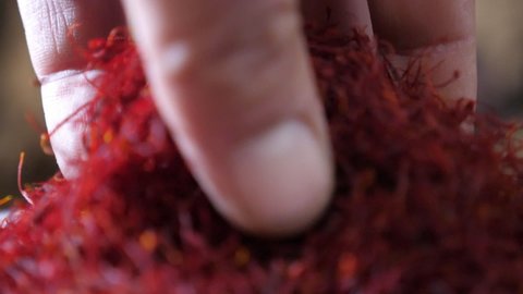 Exciting bokeh closeup of a human hand taking thin cut purple saffron and permitting it to fall in narrow stripes on plate with a healthy salad in slow motion.