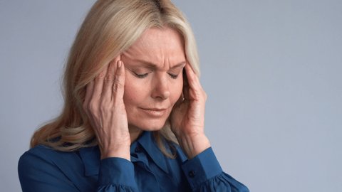 Tired stressed worried middle aged mature 50s business woman suffering from chronic headache, burnout stress, feeling migraine pain touching head. Mid age fatigue and menopause headache concept.