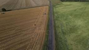 Video from a flying drone, a field with ripe cereals and haystacks, on a sunny day in summer