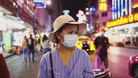 A female blogger is taking a selfie at china town. Influencers wearing masks are narrating and live. While touring and producing content in Bangkok during the outbreak. in blogger concept,4K
