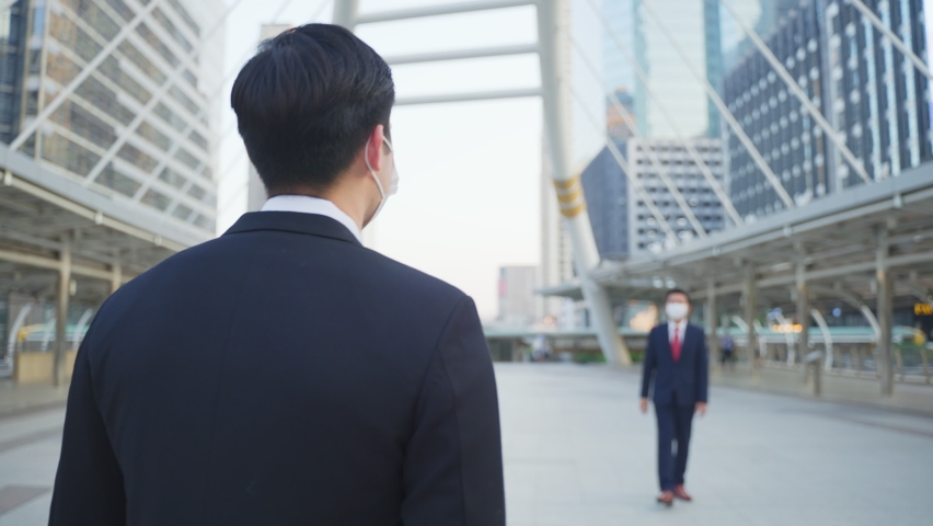 Asian business people wearing protective face mask outside in city due to covid pandemic crisis. Friends of male office workers making elbow touch instead of handshake to avoid coronavirus infection. Royalty-Free Stock Footage #1067050975