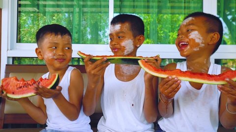 Asian boys enjoy eating watermelon together at home in summertime.