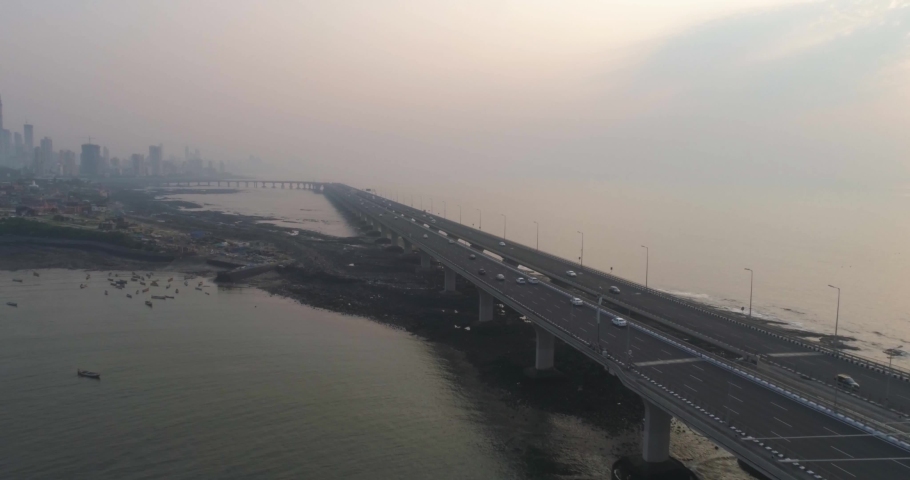 A drone shot at Bandra Worli Sea Link seen from an aerial view in slow motion. Cinematic drone movement with the iconic Mumbai Sea Link at the forefront and the city view in the background. Royalty-Free Stock Footage #1067058814