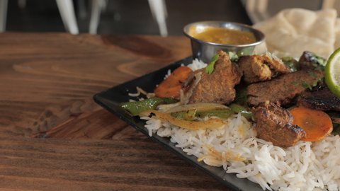 Traditional plated tandoori kabob with steak veggies over basmati rice with naan, slow motion slider close up 4K