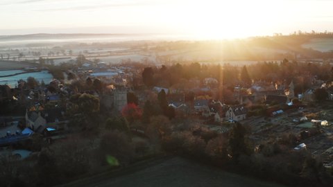 Aerial drone video of Typical English village and beautiful British countryside scenery in The Cotswolds showing a rural church at sunrise in beautiful morning light, Gloucestershire, England, UK
