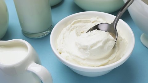 Whipped cream with spoon on blue background, greek yogurt, top view