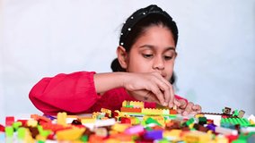 4k video of a cute little Indian girl playing with colorful toy building blocks and having fun.