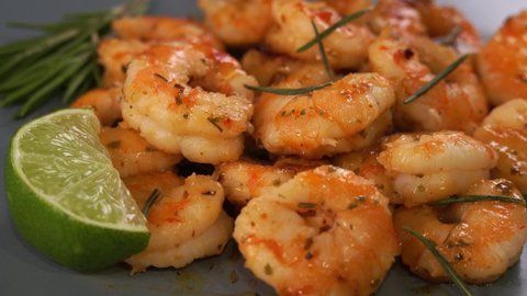 Camera movement of fried prawns in sweet and sour sauce with garlic spices and seasonings on plate with lime and raspberry. Close up of cooked Shrimps. Seafood. Macro food background.