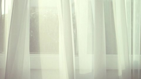 White transparent curtain on the window moved by the wind blowing. Cold and fresh air blowing through the house window and curtain. Relaxing and romantic background.