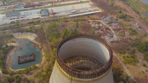 Radioactive contaminated environment in Chernobyl. Drone flies over the cooling tower near the Chernobyl nuclear power plant, backward movement. Concrete structures at the nuclear power plant.