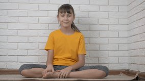 Yoga blogger. A child in namaste position talk in camera sitting on the floor.