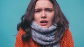 sick woman in scarf sneezing in tissue isolated on blue